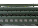 several green train cars are lined up in a row on a white surface