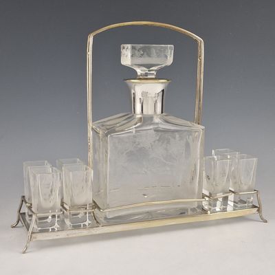 une carafe en verre plaquée argent d'époque, accompagnée de quatre verres présentés sur un plateau
