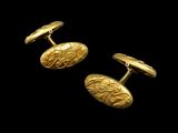 a pair of gold cufflinks on a black background