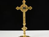 a gold cross on a white table with a black background