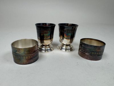 three silver cups with designs on them sitting on a white surface