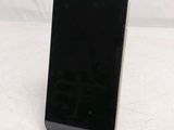 a black cell phone sitting on a stand on a white surface