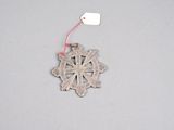 a silver ornament with a red string hanging from it