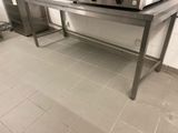 une table argentée sur laquelle se trouve un micro-ondes, dans une cuisine
