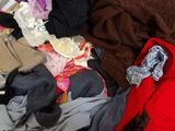 a pile of clothes on a bed with a red blanket