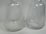 two clear glass bottles sitting next to each other on a table