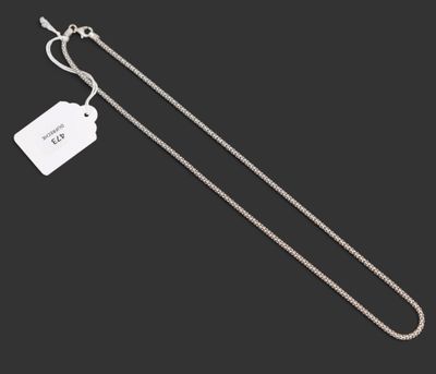 une chaîne en argent à laquelle est accrochée une médaille, sur fond noir