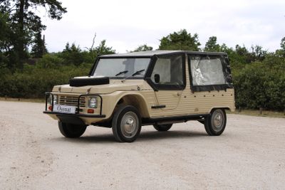 a tan vehicle parked in a parking lot with trees in the background