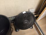 a fan that is sitting on the floor next to a trash can
