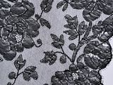 close up of a black lace fabric with flowers and leaves on it