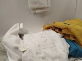 a pile of clothes sitting on top of a washer in a bathroom