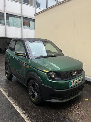une petite voiture verte garée au bord de la rue