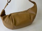 the large tan leather bag is sitting on a white surface