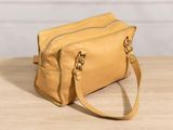 an image of a tan purse sitting on top of a wooden table