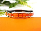 an orange and black bracelet sitting on top of an orange surface