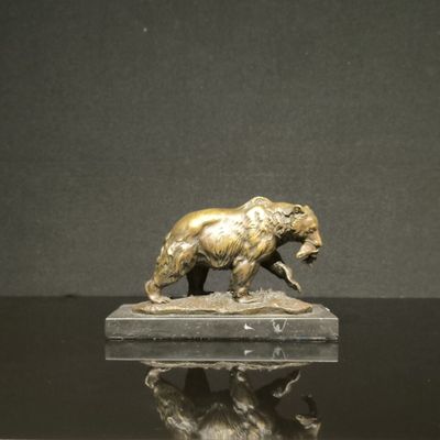 une statue en bronze représentant un ours, posée sur un socle en marbre