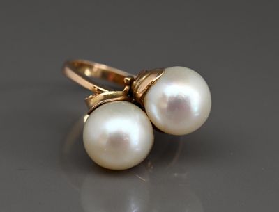 deux perles blanches sont posées sur une bague en or