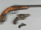 an old gun with a wooden handle and two smaller revolvers