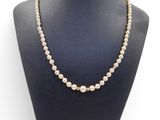 a white pearl necklace on a mannequin with a gold clasp