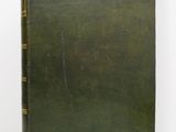 a green book sitting on top of a table next to a white wall