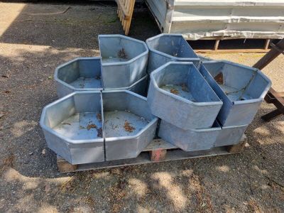 four blue buckets sitting on a pallet in the dirt