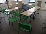 des tables et des chaises dans une salle de classe vide, avec une grande fenêtre en arrière-plan