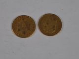 two gold coins sitting side by side on a white surface