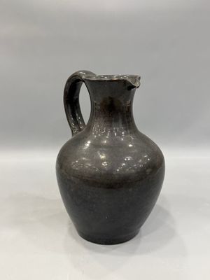 un vase noir posé sur une surface blanche