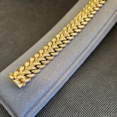 un gros plan d'un bracelet en or posé sur un étui en velours