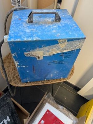 une boîte à outils bleue posée sur une chaise en osier