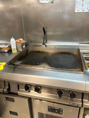 plan de travail en acier inoxydable dans une cuisine professionnelle équipée d'une cuisinière à plaque de cuisson