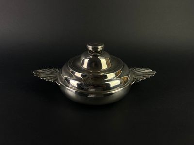 a silver plate with a lid sitting on a black surface