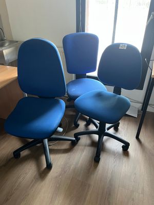 trois chaises de bureau bleues posées sur un parquet en bois massif