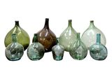 several different colored glass vases are lined up on a white surface