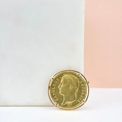 une pièce d'or posée sur une surface blanche, à côté d'un mur rose et blanc