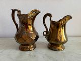 two gold pitchers sitting on a marble counter top