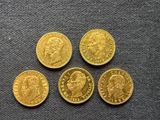 four gold sovereigns of different sizes and shapes on a gray surface