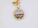 a close up of a gold necklace with a painting on it
