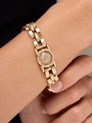 woman wearing a gold bracelet with a watch on her wrist