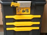 une boîte à outils noire et jaune posée sur une pile de cartons