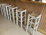 quatre tabourets blancs devant un bar équipé d'une télévision