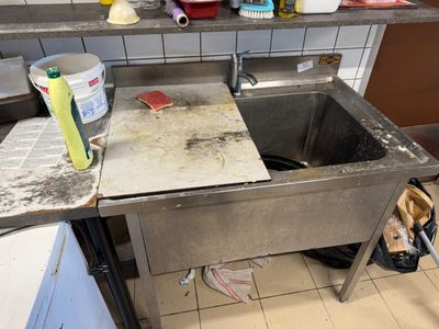 a dirty sink in the middle of a dirty kitchen