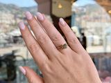 woman ' s hand holding up a ring with a yellow diamond on it