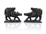 two figurines of elephants on a white surface