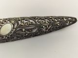 an antique silver broochet with a white stone in the center