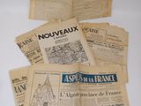 several old french newspapers sitting on top of a white table