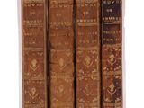quatre vieux livres sont alignés sur une surface blanche