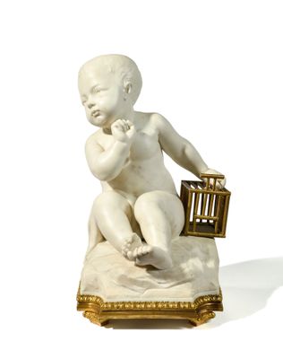 une petite statue représentant un bébé assis sur un oreiller, avec un oiseau dans une cage