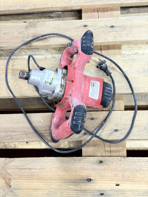 une perceuse posée sur une palette en bois, avec un cordon d'alimentation