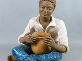 a figurine of a man sitting on the ground holding a pot